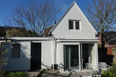 a white house with a door and a window at Ithaka Beach House, unieke plek met vrij parkeren! in Noordwijk