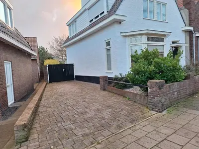 a blue house with a brick driveway in front of it at Ithaka Beach House, unieke plek met vrij parkeren! in Noordwijk