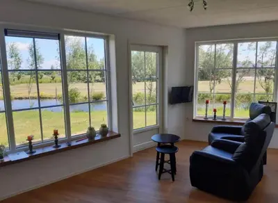 a living room with windows and a couch and a chair at Blossom Barn Lodges in Oudewater
