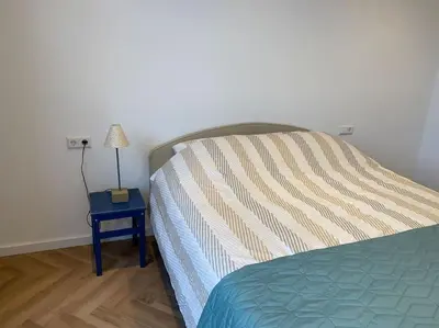 a bedroom with a bed and a nightstand with a lamp at Apartement City Center Gouda: View Deluxe in Gouda