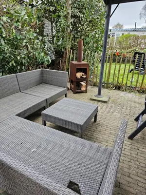 a patio with two benches and a table and an umbrella at Slapen in Tuitje in Tuitjenhorn
