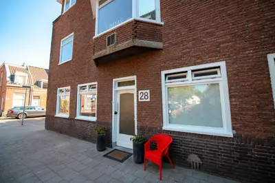 a red chair sitting outside of a brick building at Hello Stay Utrecht in Utrecht