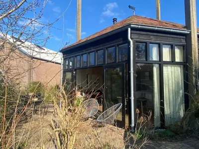 a glass house with two chairs in a garden at Ons Huisje Achter - De Hooischuur in Noordwijkerhout