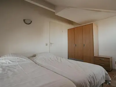 a bedroom with a bed and a wooden cabinet at Busch en Dam in Uitgeest