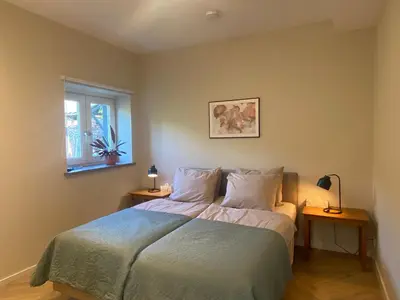 a bedroom with a bed with two tables and a window at Ons Huisje Achter in Noordwijkerhout