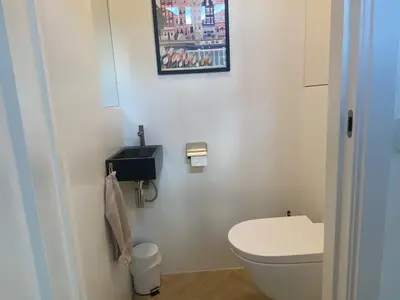 a bathroom with a toilet and a picture on the wall at Ons Huisje Achter in Noordwijkerhout