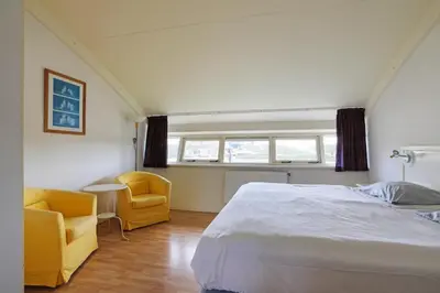 a bedroom with a bed and two yellow chairs at Appartement Zandkorrel in Schoorl