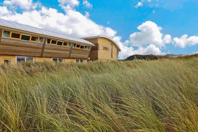 a building on top of a field of tall grass at Appartement Zandkorrel in Schoorl