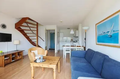 a living room with a blue couch and a table at Appartement Zandkorrel in Schoorl