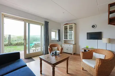 a living room with a couch and chairs and a table at Appartement Zandkorrel in Schoorl