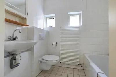 a white bathroom with a toilet and a sink at Appartement Zandkorrel in Schoorl