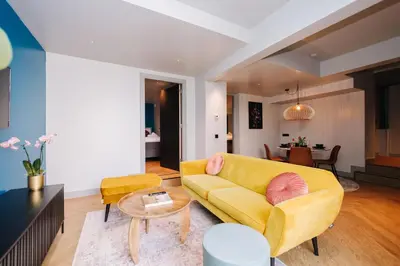 a living room with a yellow couch and a table at Hotel Keur - Apartments in Zandvoort