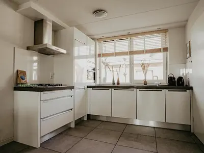 a kitchen with white cabinets and a window at Dorregeest in Uitgeest