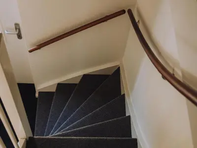a staircase with black treads and a wooden rail at Dorregeest in Uitgeest