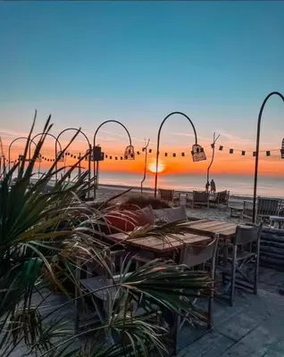 a beach with tables and chairs and a sunset at Noordster Beachhouse, Noordwijk aan Zee in Noordwijk