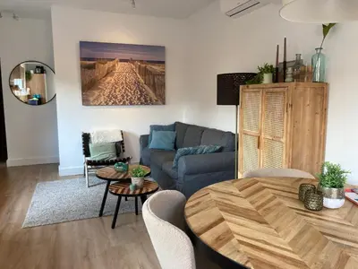 a living room with a blue couch and a table at Noordster Beachhouse, Noordwijk aan Zee in Noordwijk