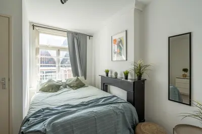 a bedroom with a bed with a mirror and a window at Penthouse Amsterdam Dam Square in Amsterdam