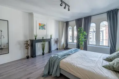 a bedroom with a large bed and some windows at Penthouse Amsterdam Dam Square in Amsterdam