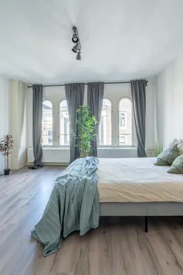 a bedroom with a large bed and windows at Penthouse Amsterdam Dam Square in Amsterdam