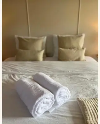 two towels on a white bed with pillows at Huisje Marie in Zandvoort