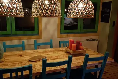 a dining room table with blue chairs and lights at Balistyle guesthouse incl Jacuzzi near Amsterdam and Schiphol in Vijfhuizen