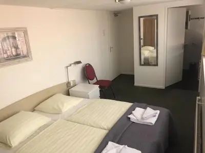 a hotel room with a bed and a red chair at Hotel Anna in Zandvoort