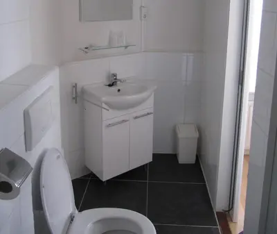 a white bathroom with a toilet and a sink at Hotel Anna in Zandvoort