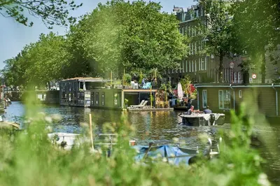 a man is sitting in a boat on a canal at The Amsterdam Houseboat Family - de Pijp in Amsterdam