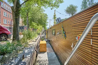 a sidewalk with a wooden wall with plants on it at The Amsterdam Houseboat Family - de Pijp in Amsterdam