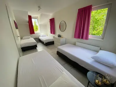 a bedroom with two beds and red curtains at Villa Riverside met hottub, eigen aanlegsteiger, zwemtrap, trampoline en kano's in Zeewolde