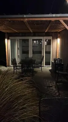 a porch with benches and a table at night at Villa Riverside met hottub, eigen aanlegsteiger, zwemtrap, trampoline en kano's in Zeewolde