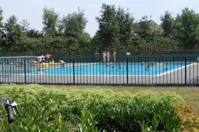 a pool with people in it with people in it at Villa Riverside met hottub, eigen aanlegsteiger, zwemtrap, trampoline en kano's in Zeewolde