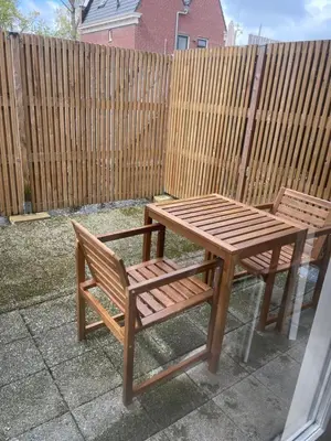 a wooden table and two chairs next to a wooden fence at Molenzicht in Alkmaar