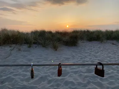 a pole on the beach with the sunset in the background at Studio Eb in Egmond aan Zee