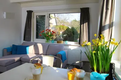 a living room with a couch and a table with flowers at Zomerhuis Flow in Egmond aan Zee