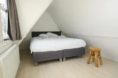 a small bedroom with a bed and a stool at Zomerhuis Flow in Egmond aan Zee