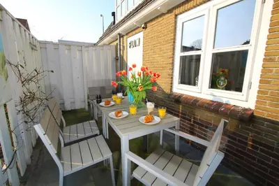 a table and chairs on a patio with flowers at Zomerhuis Flow in Egmond aan Zee