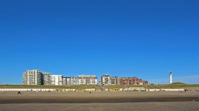 a group of people on a beach with buildings in the background at Zomerhuis Flow in Egmond aan Zee