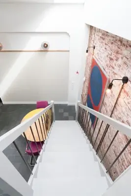 a room with a staircase with a chair and a brick wall at Pakhuis aan de Zaan in Wormerveer
