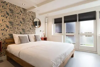 a bedroom with a large white bed and windows at Pakhuis aan de Zaan in Wormerveer