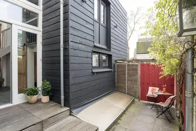 a black house with a patio and a red door at Pakhuis aan de Zaan in Wormerveer