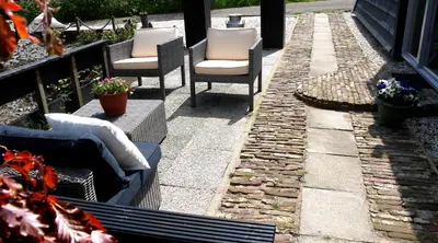 a patio with three chairs and a table and a fire place at Markermeerlogies in Bovenkarspel