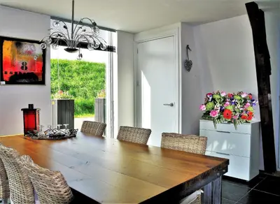 a dining room with a wooden table and flowers at Markermeerlogies in Bovenkarspel