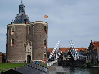 a large brick building with a clock tower next to a river at Markermeerlogies in Bovenkarspel