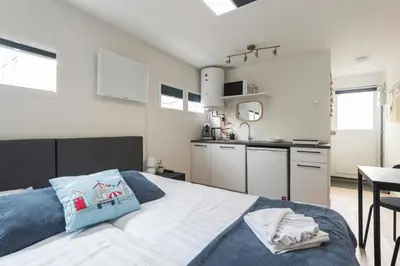 a bedroom with a bed and a kitchen at Milis Beach Cottage in Zandvoort