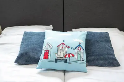a pillow with a house on it on a bed at Milis Beach Cottage in Zandvoort