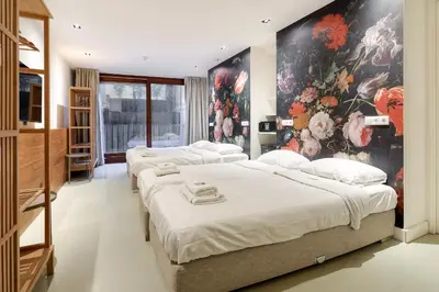 four beds in a room with a painting on the wall at Marnix360apartments The Mansion Suites in Amsterdam