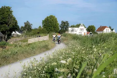 two people riding bikes down a dirt road at Aan de Amstel in De Kwakel