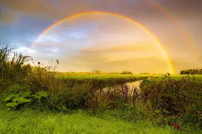 a rainbow in the sky over a field at Aan de Amstel in De Kwakel