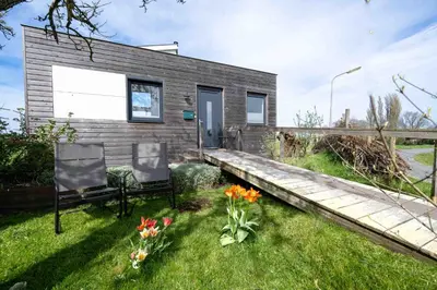 a tiny house with two chairs in the grass at Aan de Amstel in De Kwakel